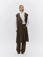 Person wearing a brown vest and pants with a white shirt on a white background