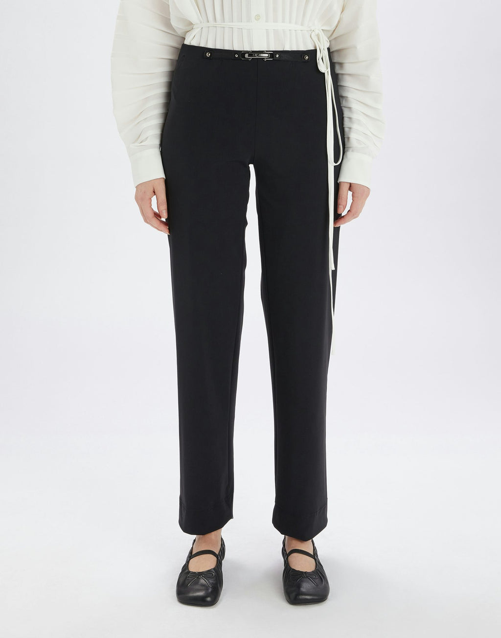 Person wearing black pants and a white sweater on a white background