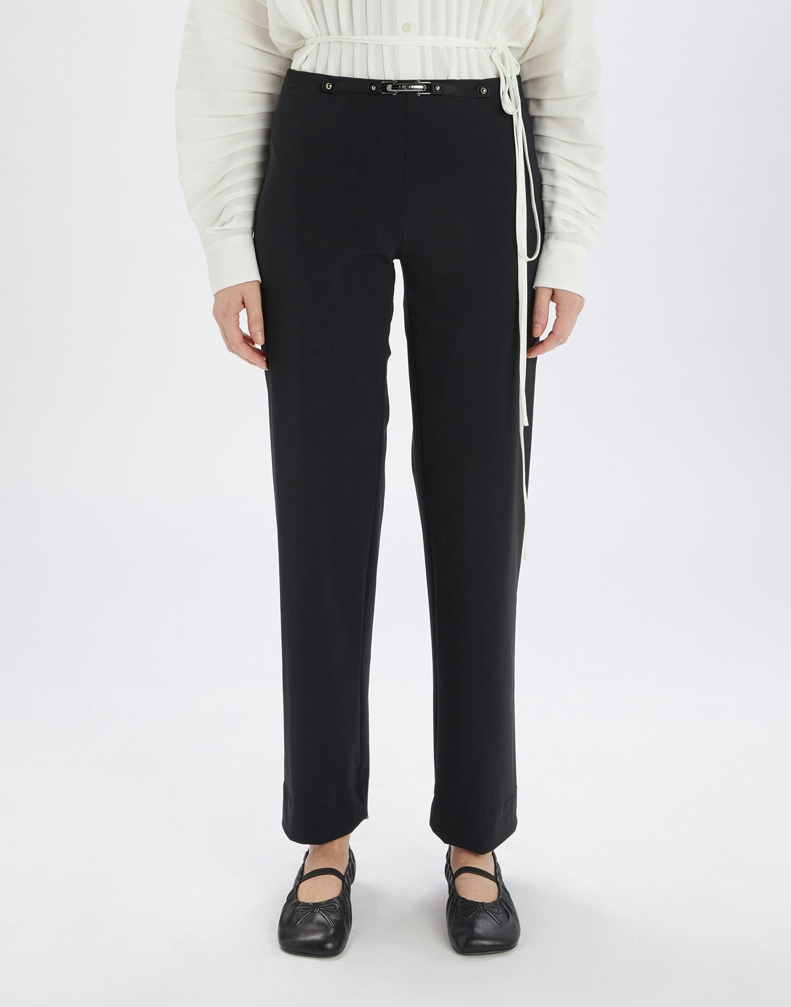 Person wearing black pants and a white sweater on a white background