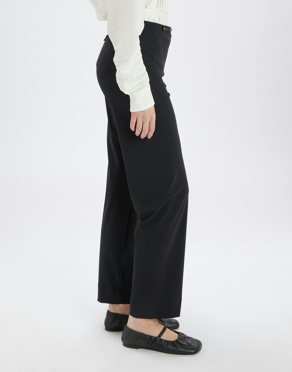 Person wearing black wide-leg pants and a white top on a white background