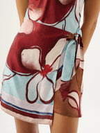 Colorful floral-patterned dress with a tie waist on a white background