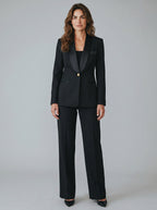 Woman wearing a black suit with a tuxedo jacket on a gray background