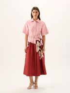 Woman wearing a pink and red dress with floral patterns on a white background