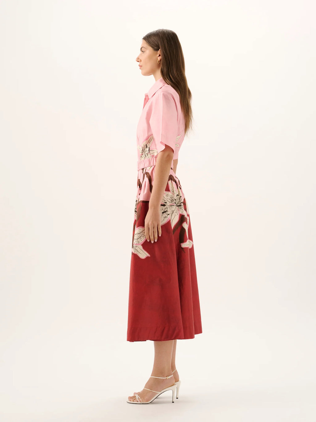 Woman wearing a pink blouse and red skirt with floral patterns on a white background