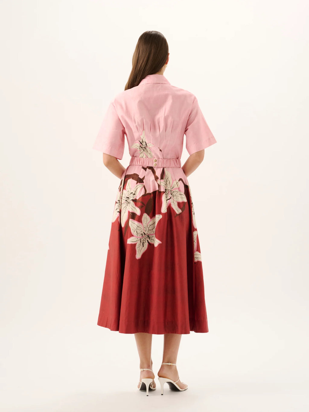 Woman wearing a pink and red dress with floral patterns on a white background