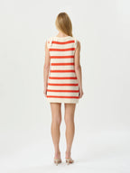 Woman wearing a red and white striped dress on a plain background