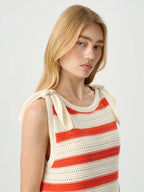 Woman wearing a sleeveless crochet top with red and white stripes on a plain background