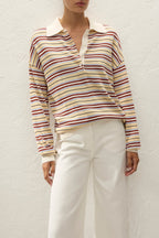Person wearing a striped long-sleeve shirt and white pants against a light background