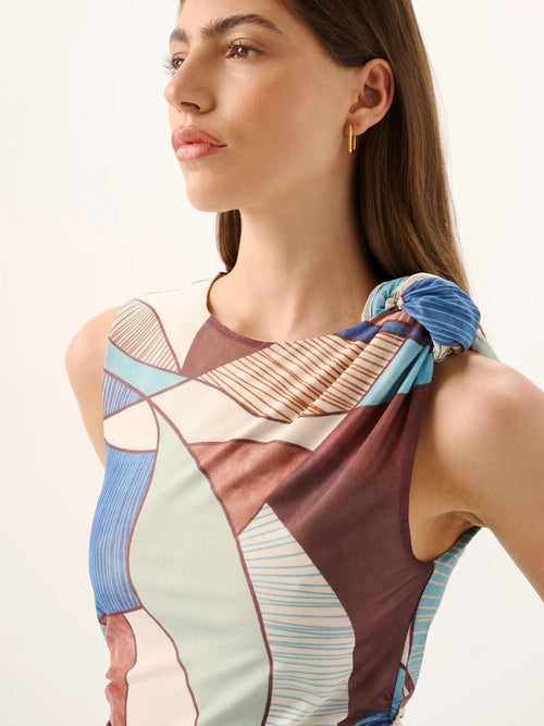 Woman wearing a colorful geometric-patterned top with a plain background