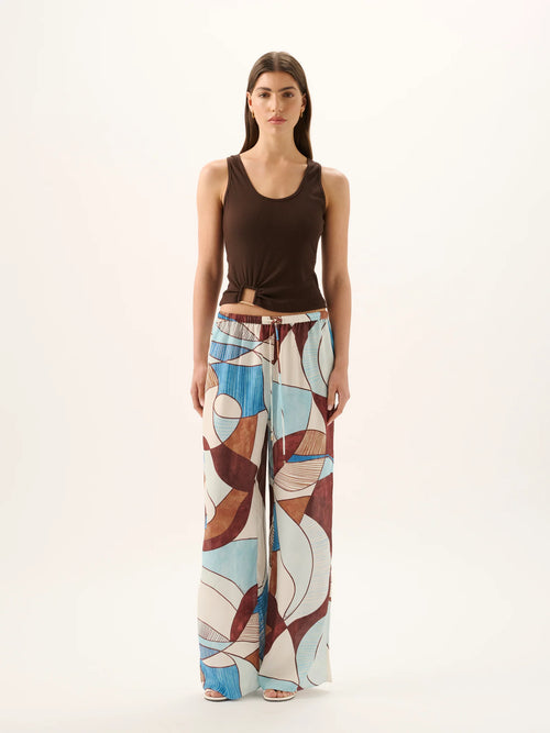 Woman wearing a brown top and colorful wide-leg pants on a white background