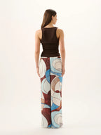 Woman wearing a sleeveless top and patterned pants on a white background