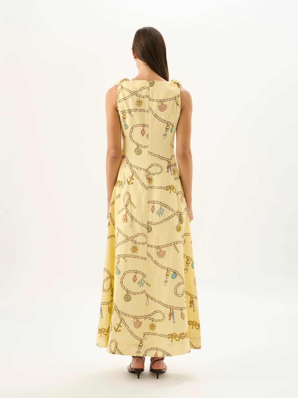 Woman wearing a long, light-colored dress with a pattern on a white background