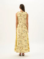Woman wearing a long, light-colored dress with a pattern on a white background