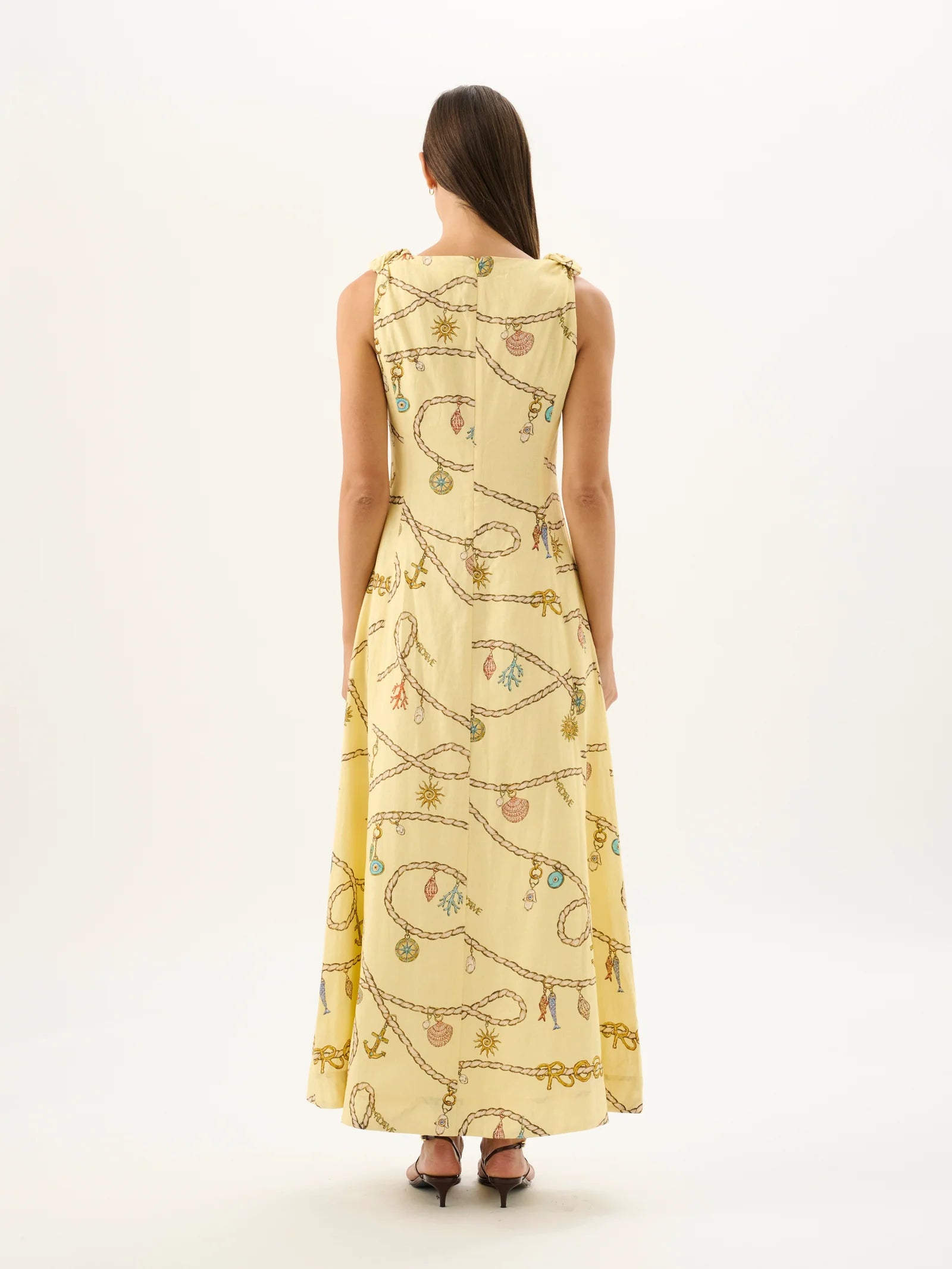 Woman wearing a long, light-colored dress with a pattern on a white background