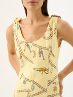 Woman wearing a yellow sleeveless dress with decorative patterns on a white background