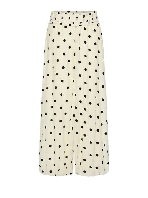 A pair of wide-leg cropped pants in a cream-colored fabric with a black polka dot pattern, shown against a light gray background.