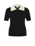 A black short-sleeve knit top with a contrasting cream-colored pointed collar, shown on a light gray background.