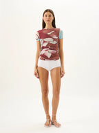 Woman wearing a floral top and white shorts on a white background