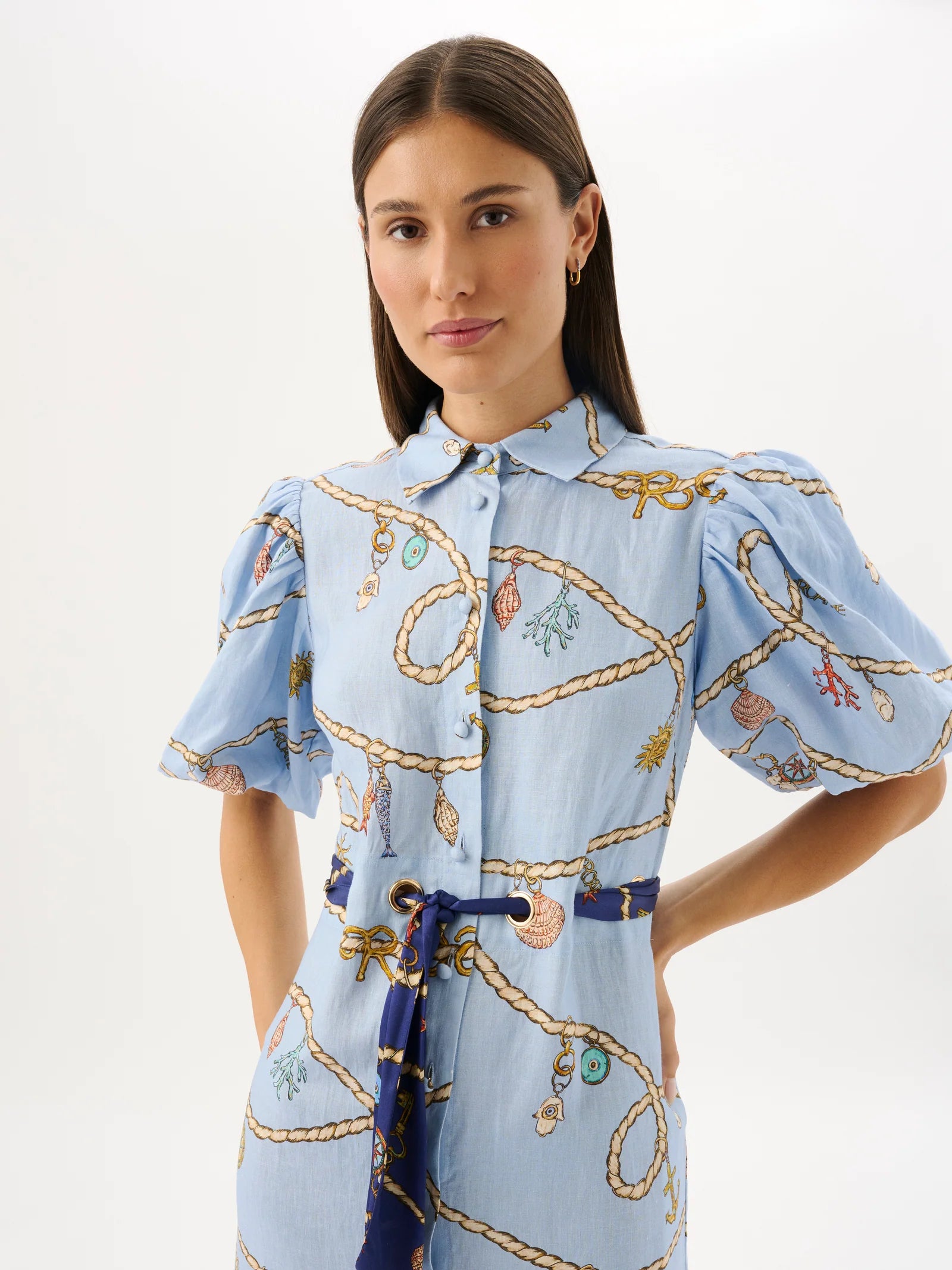 Woman wearing a light blue dress with decorative patterns on a white background