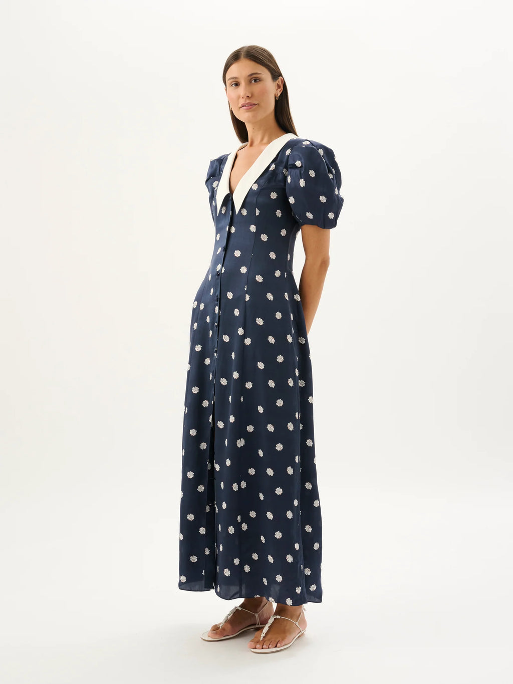 Woman wearing a navy dress with white polka dots on a white background