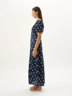 Woman wearing a navy dress with white polka dots on a white background