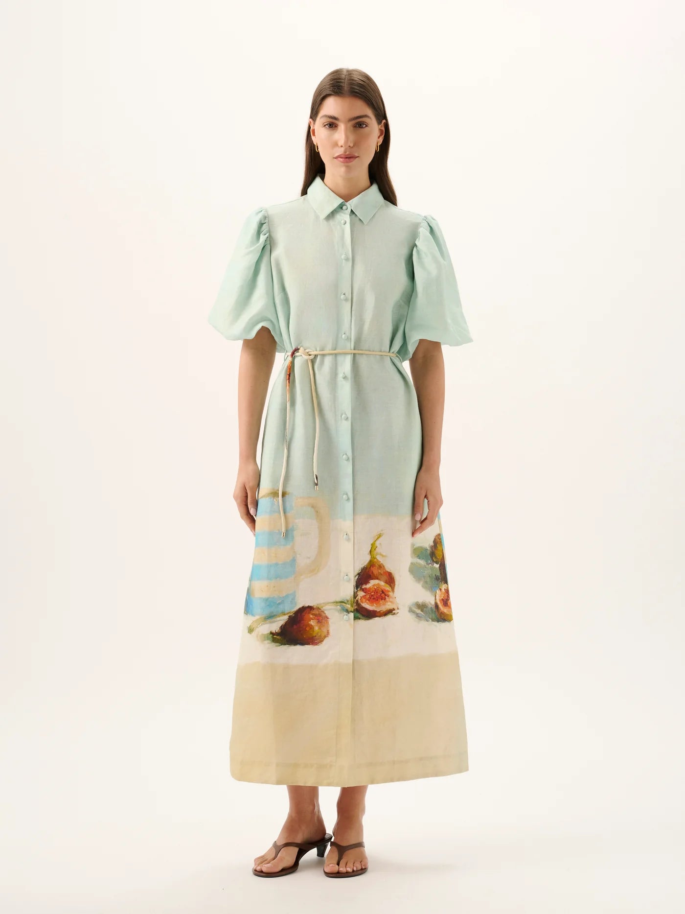 Woman wearing a light green dress with a printed skirt on a white background