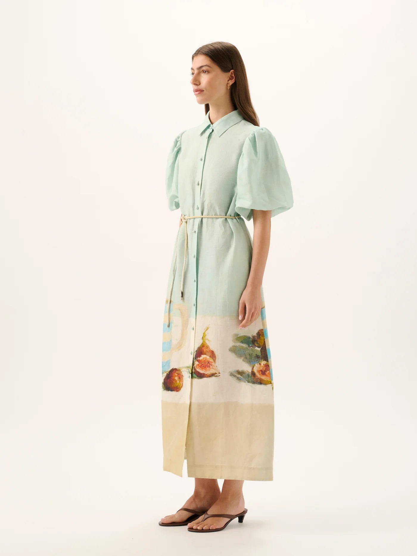 Woman wearing a light green dress with a colorful skirt on a white background
