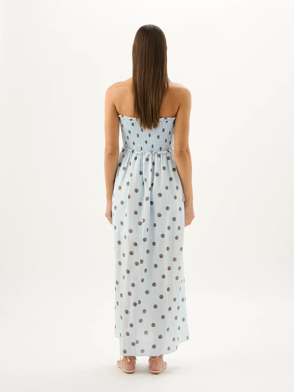 Woman wearing a strapless polka dot dress on a white background