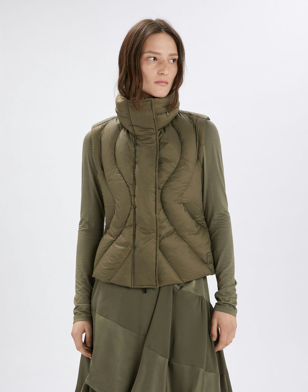 Woman wearing a green quilted jacket on a white background