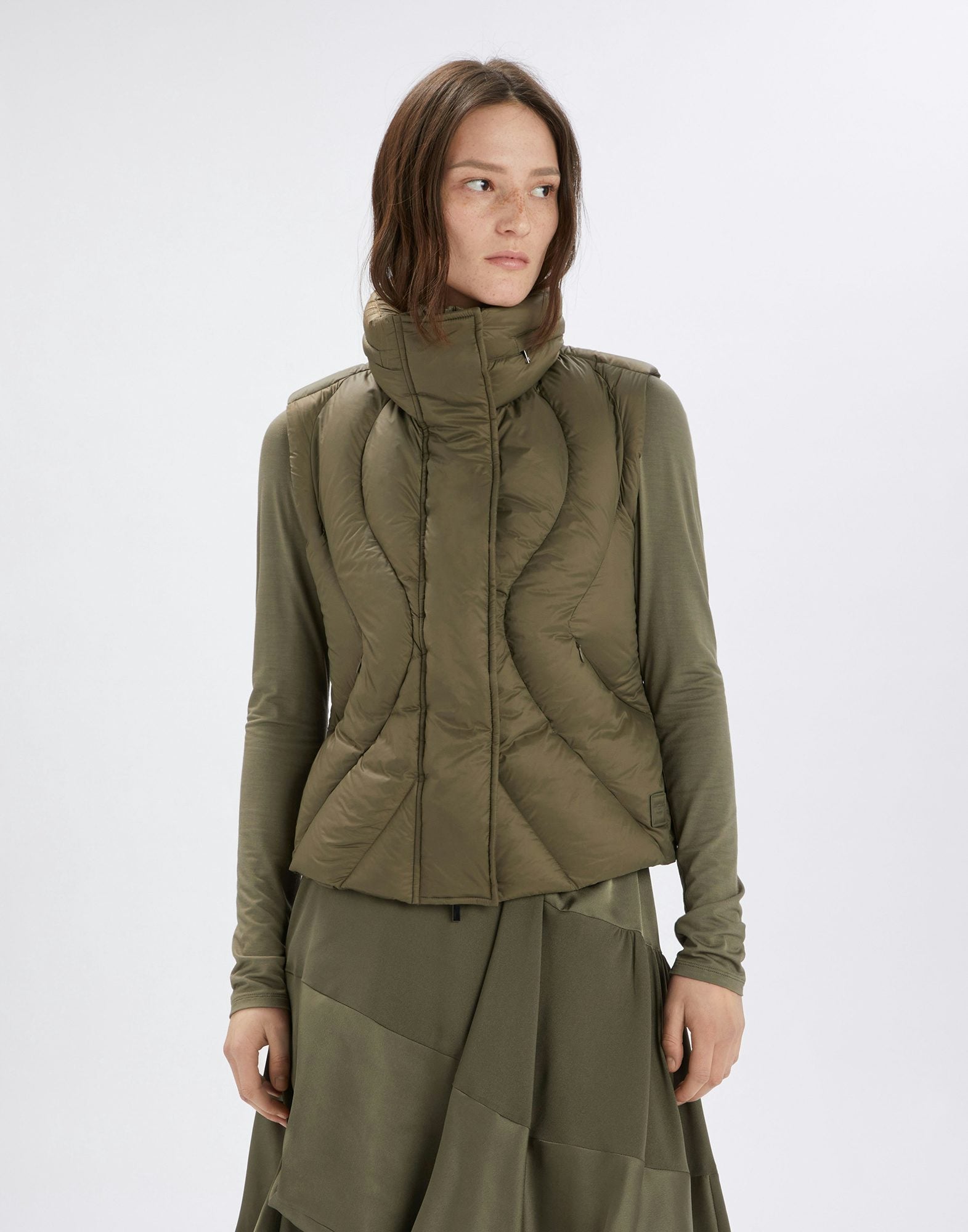 Woman wearing a green quilted jacket on a white background