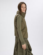 Person wearing a green outfit with a puffer vest on a white background