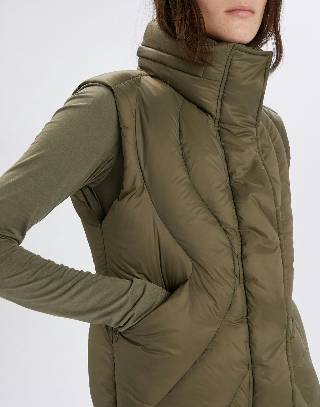 Green puffer vest worn by a person on a white background
