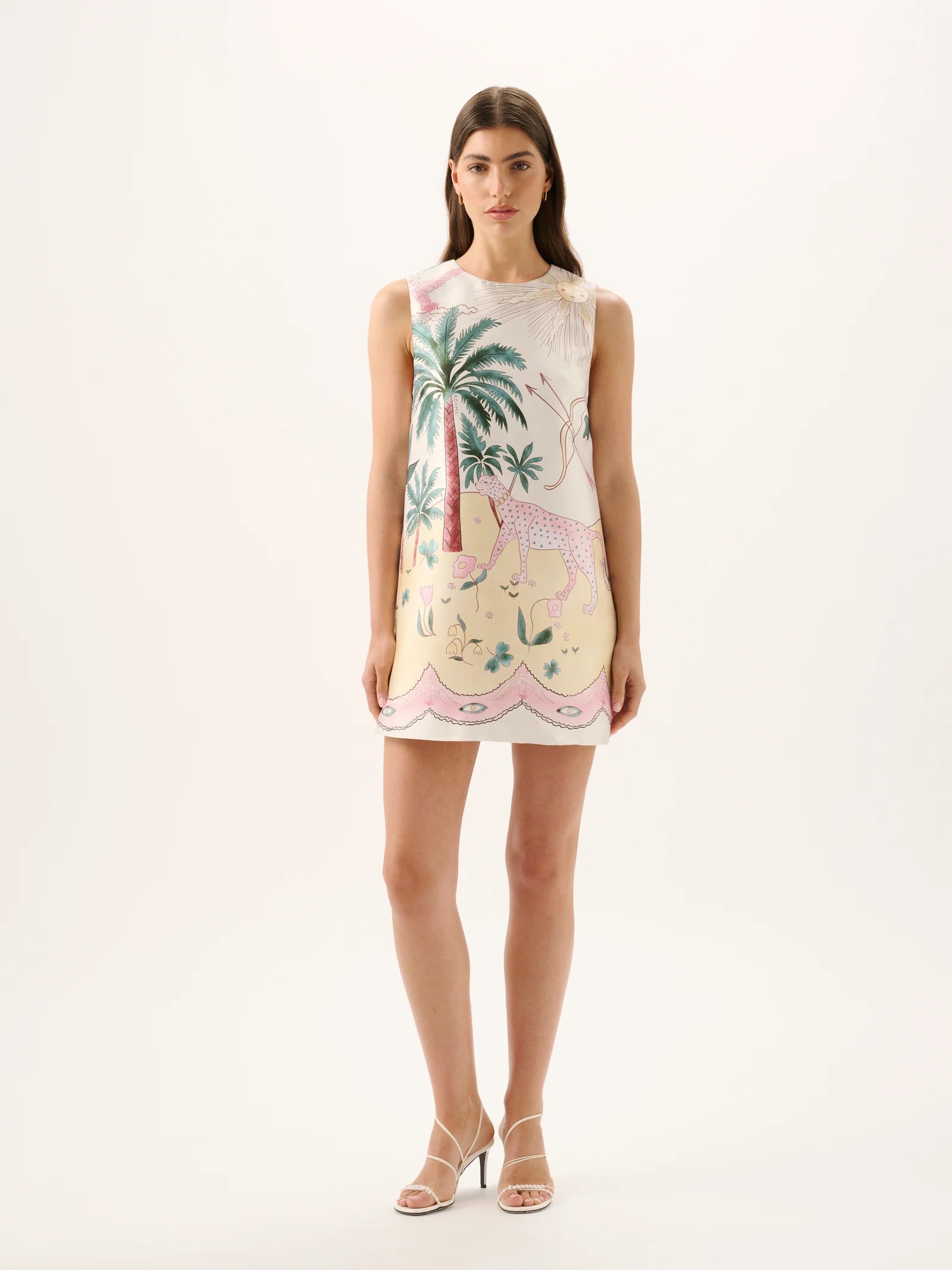 Woman wearing a sleeveless dress with palm tree and flamingo design on a white background