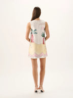 Woman wearing a sleeveless dress with floral and pineapple design on a white background