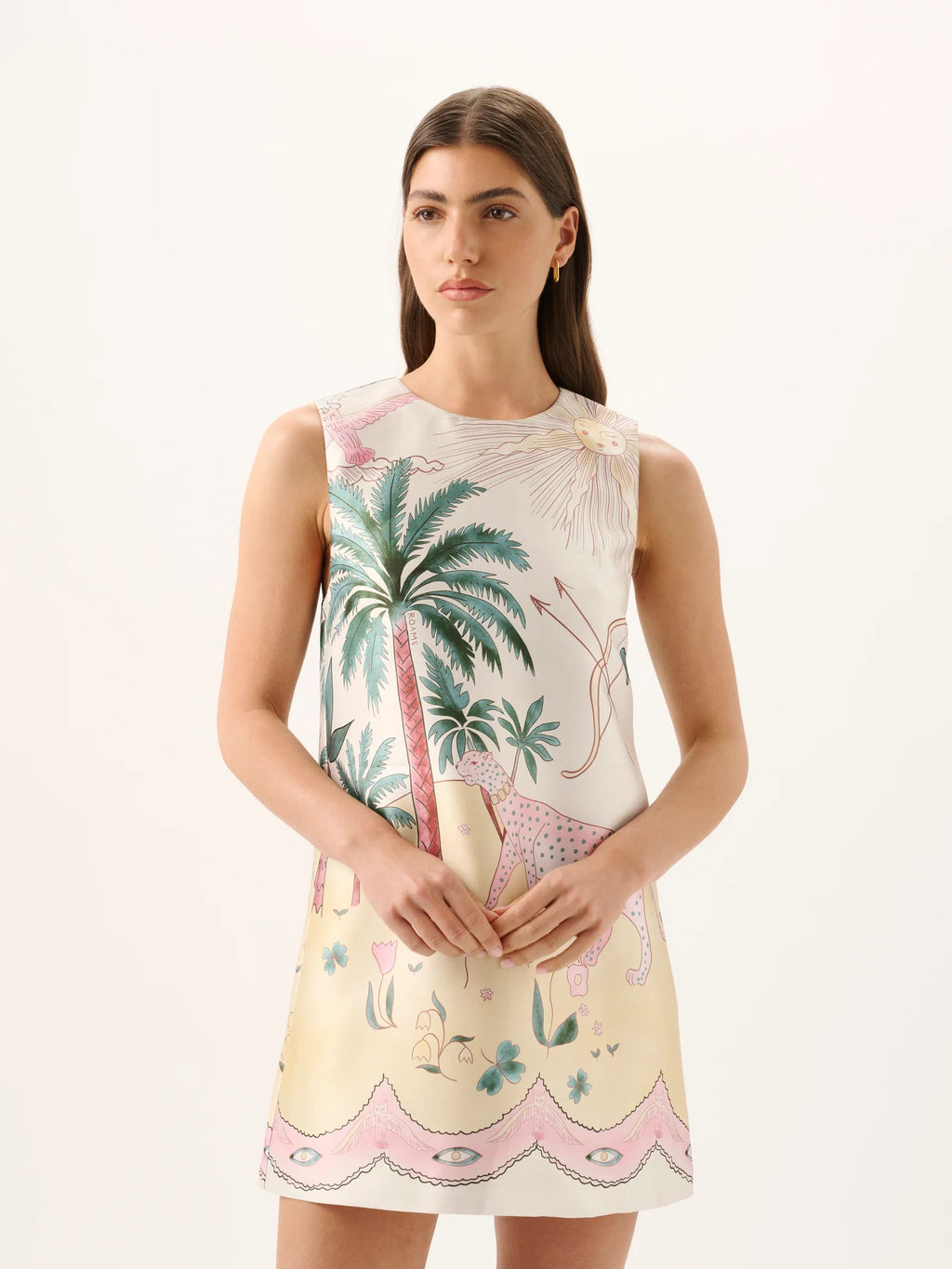 Woman wearing a sleeveless dress with palm tree and floral pattern on a white background