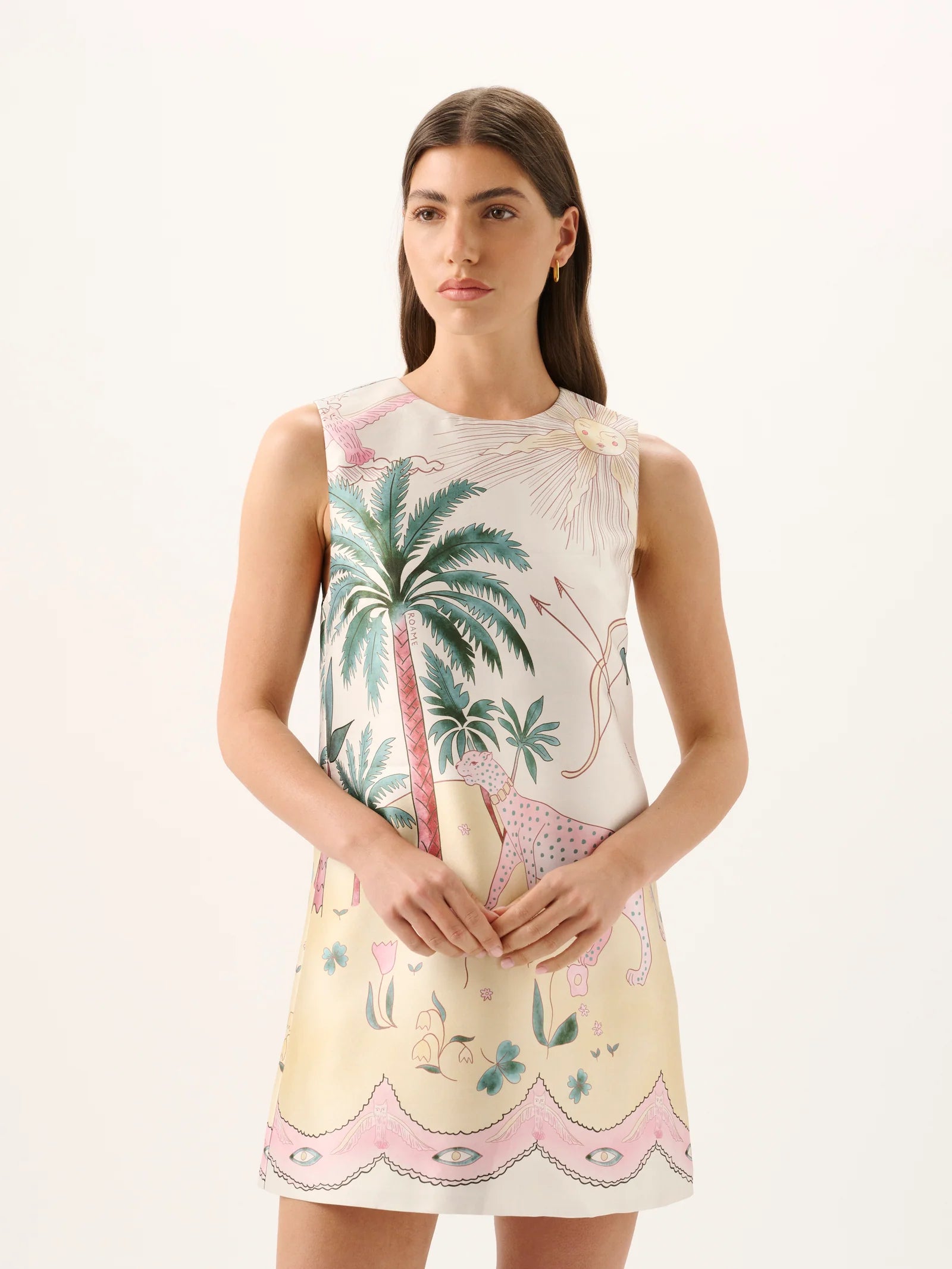 Woman wearing a sleeveless dress with palm tree and floral pattern on a white background