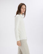 Person wearing a white high-neck sweater and beige pants on a white background