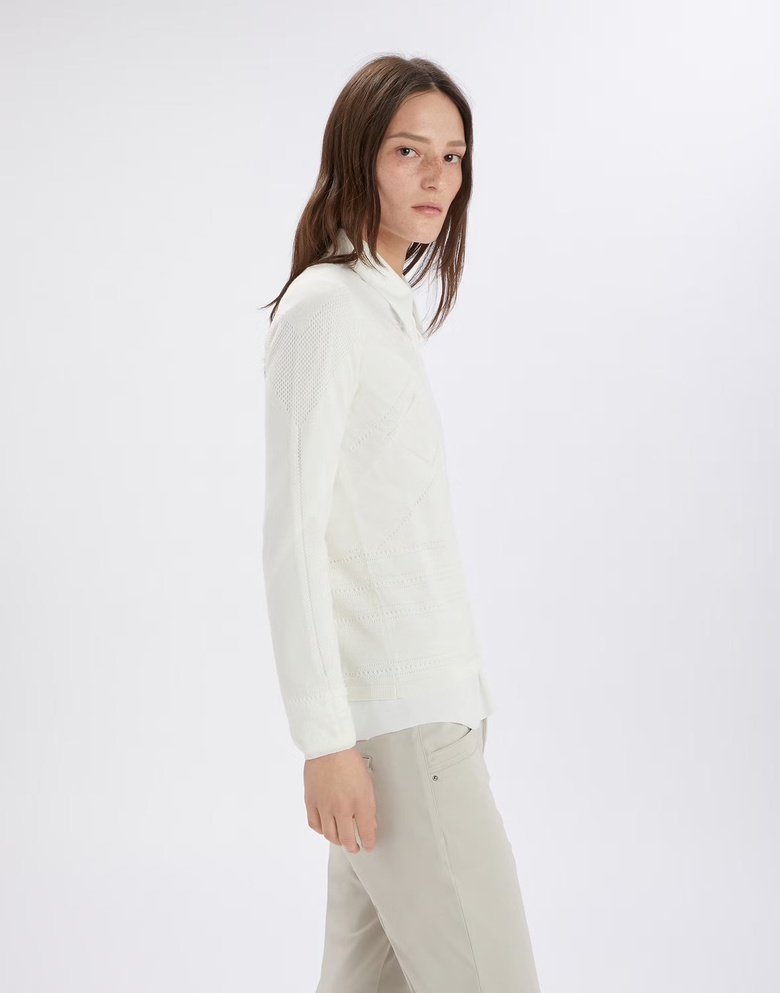 Person wearing a white high-neck sweater and beige pants on a white background