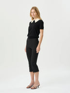Woman wearing a black outfit with a white collar on a white background