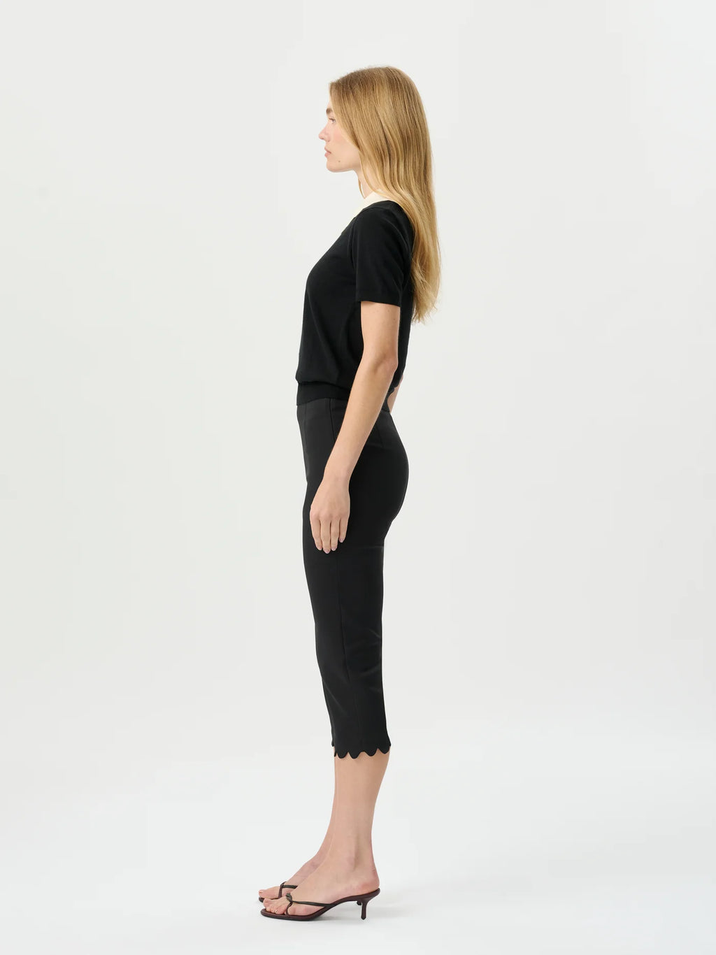 Woman wearing a black top and black capri pants on a white background
