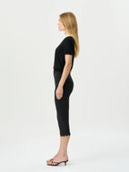 Woman wearing a black top and black capri pants on a white background