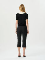 Woman wearing a black outfit with white lace details on a white background
