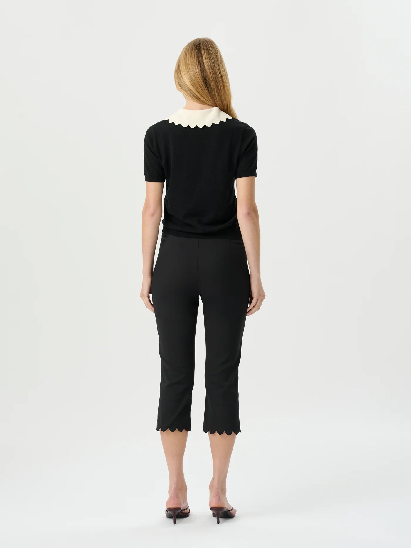 Woman wearing a black outfit with white lace details on a white background