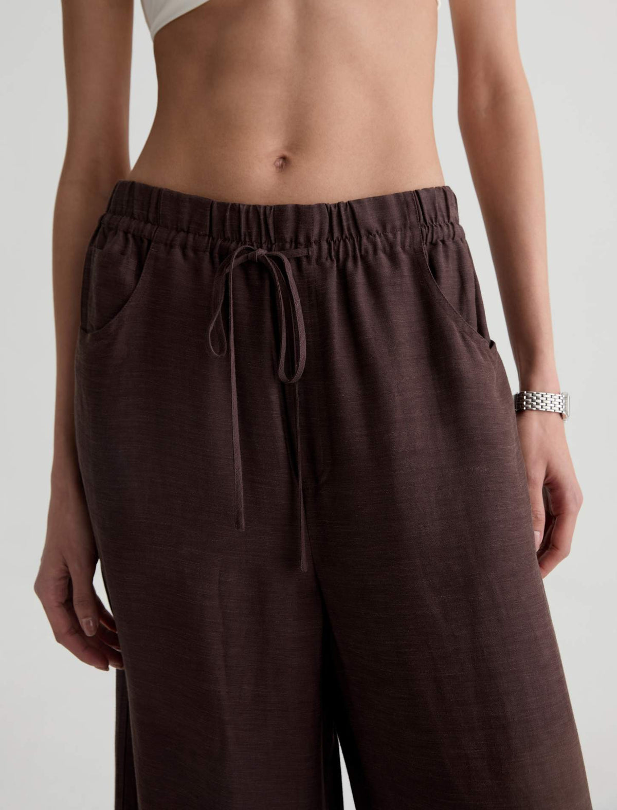 Brown drawstring pants worn by a person on a plain background