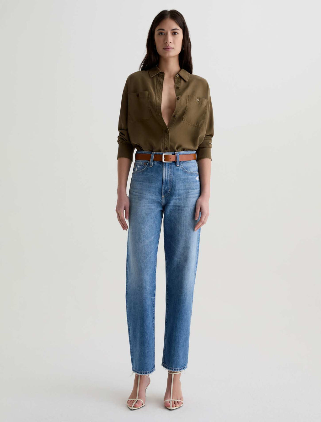 Woman wearing a green shirt and blue jeans on a white background