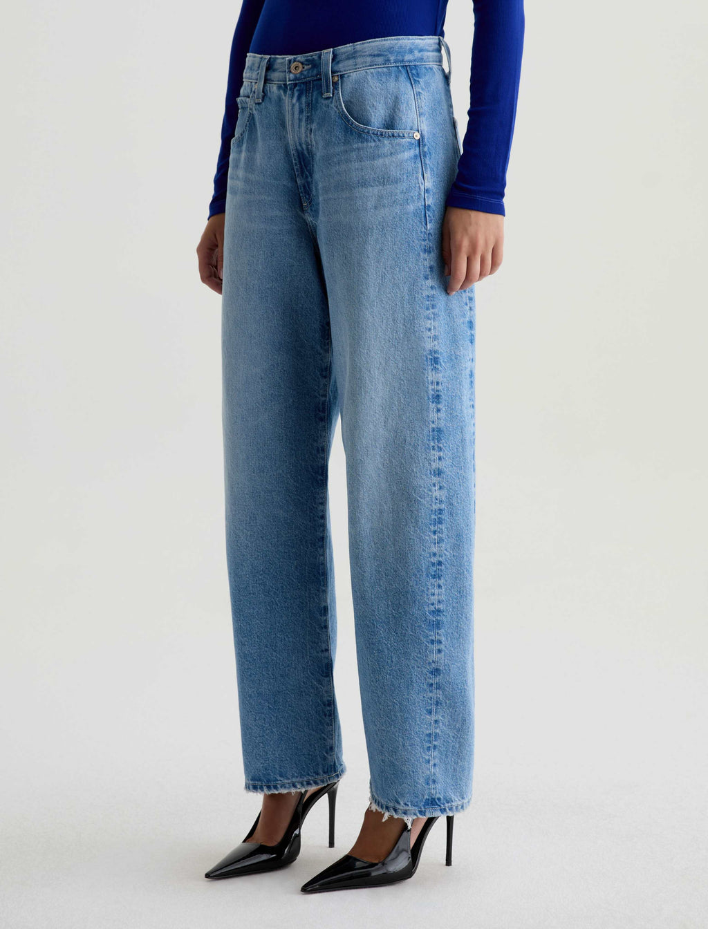 Person wearing light blue jeans and black shoes on a white background