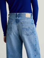 Person wearing blue jeans and a blue shirt on a light gray background