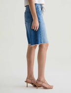 Person wearing a blue denim skirt on a white background