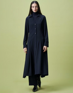 A model wearing a navy shirt dress with a V-neck, mother-of-pearl buttons, long sleeves with split turn-up cuffs, and side vents at the knee.