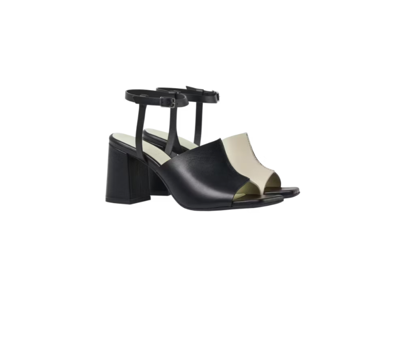 A pair of black and white stacked heel sandals with adjustable ankle straps and a silver metal buckle.